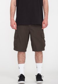 Mørkebrune cargoshorts med to sidelommer, lavet af slidstærkt stof. Parret med hvide sokker og sorte sneakers.