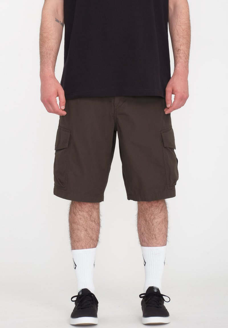 Mørkebrune cargoshorts med to sidelommer, lavet af slidstærkt stof. Parret med hvide sokker og sorte sneakers.