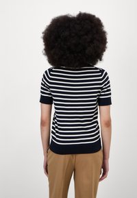 Tričko s krátkým rukávem v námořnické modré a bílé pruhované barvě, s žebrovaným výstřihem a lemem. Měkký, lehký materiál s přiléhavým střihem.
