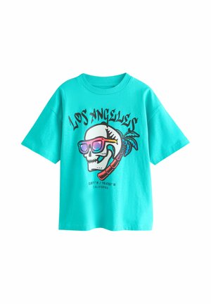 Turkusowa koszulka z czaszką noszącą tęczowe okulary przeciwsłoneczne, palmą za nią oraz napisem „Los Angeles” i współrzędnymi Kalifornii.