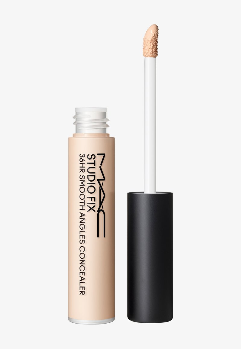 Correcteur MAC Studio Fix 36HR Smooth Angles avec liquide beige et applicateur éponge incliné, bouchon noir retiré à côté du tube.