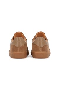 Beige semišové tenisky s hladkou hnědou gumovou podešví, které mají minimalistický design a zaoblené detaily na podpatku. Logo embosované na zadní straně.