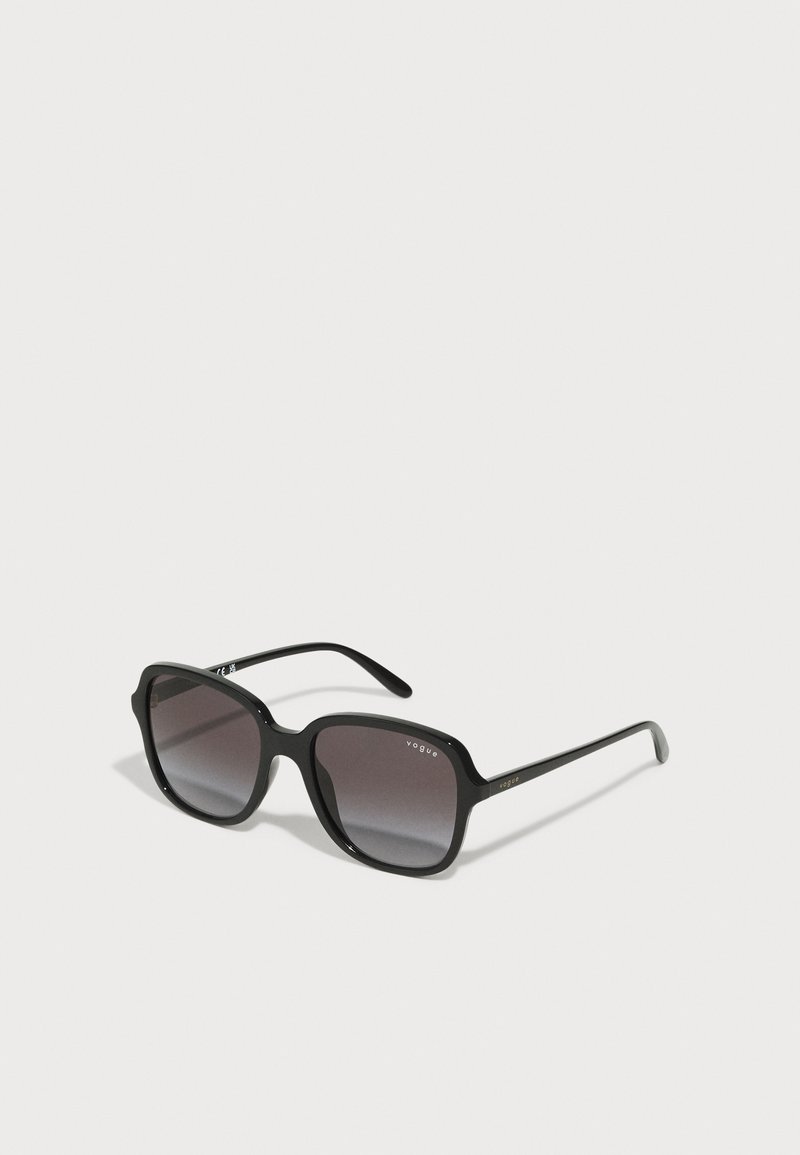 Óculos de sol oversized pretos com lentes degradê, cantos arredondados e hastes pretas finas com detalhes em logotipo dourado.