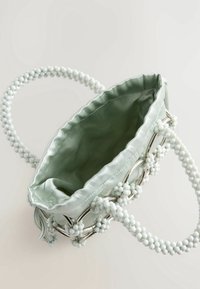 Sac en satin vert clair avec poignée en perles blanches ; équipé de ferrures argentées et d'un intérieur doux et texturé. Le design ouvert met en valeur l'intérieur spacieux.