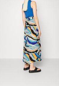 Lång, flödande maxikjol med ett färgglatt abstrakt vågmönster i nyanser av blått, gult och svart. Har resårmidja och sidofrans.