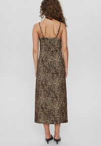 Vestido maxi de estampado de leopardo con finas tirantes ajustables, corsé ajustado y falda fluida. Hecho de un tejido suave con una textura lisa.