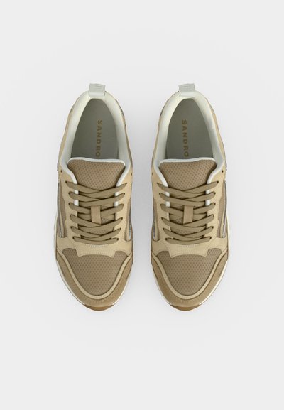 Ζευγάρι μπεζ και καφέ sneakers με κορδόνια, πλέγμα επάνω μέρος και επενδεδυμένο γιακά, από ψηλά σε λευκό φόντο.