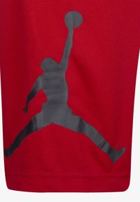 Pantalones cortos deportivos rojos hechos de una tela transpirable, con un gran logo negro de Jumpman impreso en el lateral. Superficie ligera y texturizada.