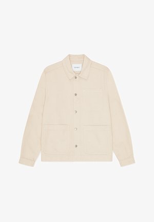 Világos bézs színű dzseki, texturált anyagból készült. Hegyes gallérral, elöl gombos záródással és két nagy elülső zsebbel rendelkezik.