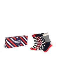 Vier Paare Baumwollsocken in verschiedenen Mustern: rot und marineblau gestreift, mit Punkten und einer Mischung aus rot, creme und marineblau. Die Box hat diagonale Streifen.