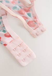 Lyserød bh-strop med jordbærmønster, der har blødt tekstureret stof og en lukning med flere kroge for justerbar pasform.