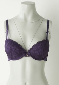 Paarse kant beha met gewatteerde cups, verstelbare schouderbanden, geschulpte randen en een klein decoratief hanger in het midden. De zijkanten hebben stofpanelen.