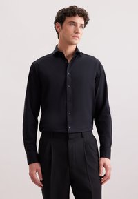 Camicia nera a maniche lunghe con colletto a button-down, tessuto liscio e bottoni abbinati, abbinata a pantaloni neri su misura.