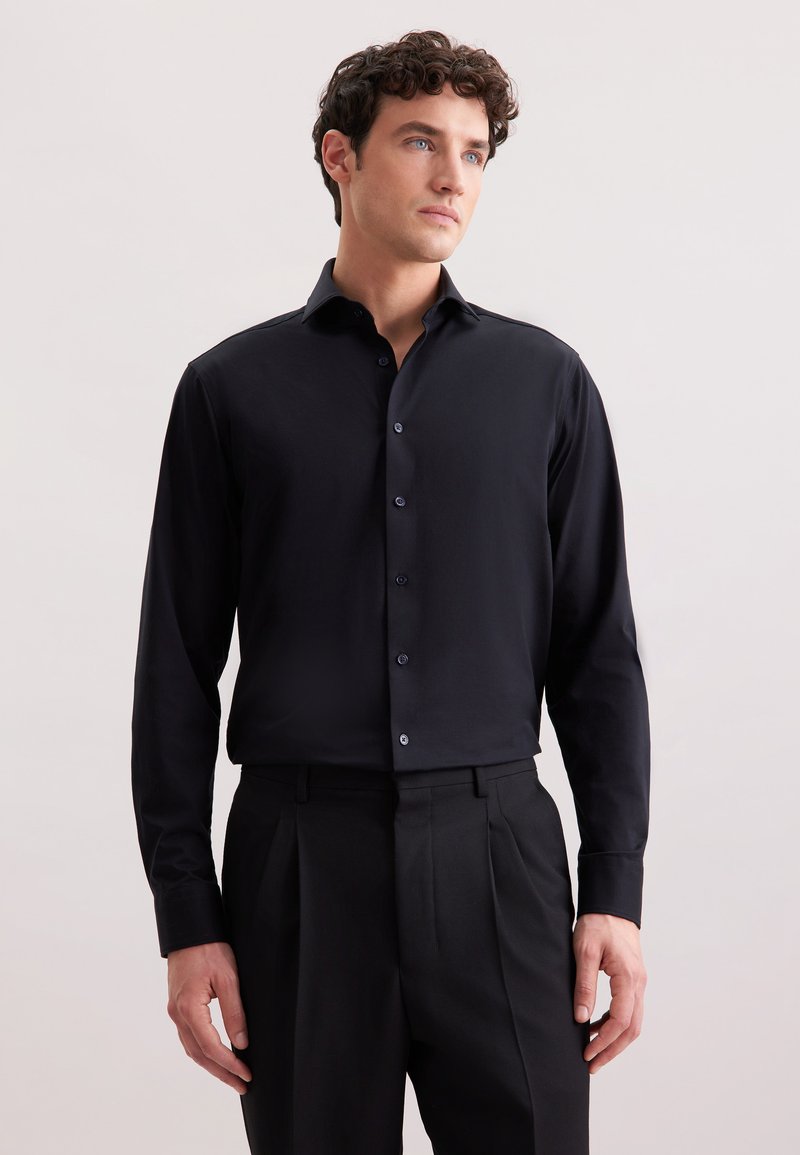 Camicia nera a maniche lunghe con colletto a button-down, tessuto liscio e bottoni abbinati, abbinata a pantaloni neri su misura.