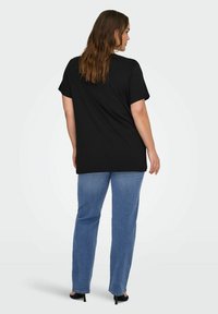 Czarny bawełniany t-shirt z krótkim rękawem, luźny krój, okrągły dekolt, połączony z jasnoniebieskimi dżinsami o prostym kroju oraz czarnymi butami na obcasie.