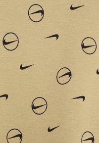 Žlutá tkanina s opakujícím se vzorem černých log swosh od Nike a kruhovými obrysy. Hladká textilie s jemným pleteným vzorem.