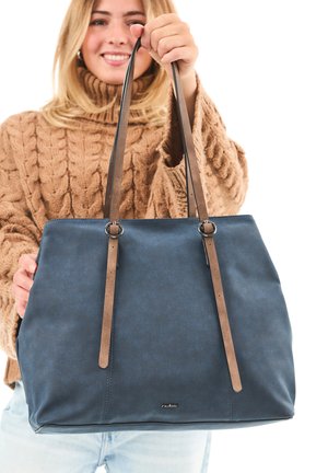 Dark blue tote bag made of textured material, featuring long brown leather straps, silver hardware accents, and a logo in the lower center.