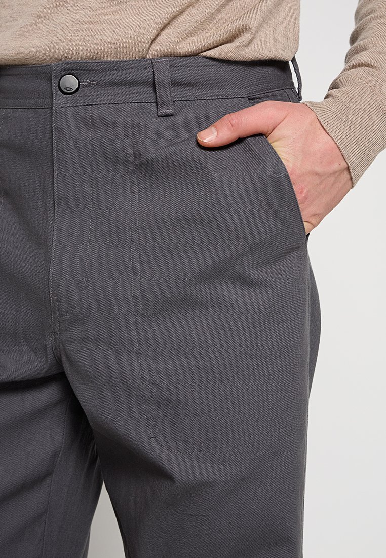 Pantalones de algodón grises con una textura suave, cierre de botón, bolsillos laterales y corte ajustado, con costuras sutiles a lo largo de las costuras.