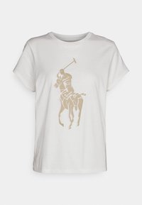 Bílé bavlněné tričko s kulatým výstřihem, zdobené béžovým grafikou hráče polo a nápisem přes hrudník. Krátké rukávy.