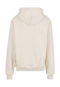 Krémová mikina s měkkou texturou, vybavená kapucí na šňůrku, dlouhými rukávy a žebrovanými manžetami na pase a rukávech.