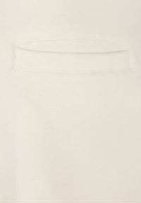 Primer plano de una tela de algodón crema que presenta un pequeño bolsillo rectangular con un contorno cosido, textura suave y diseño minimalista.