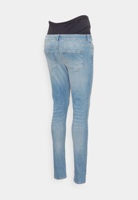 Jeans slim-fit azul claro com uma cintura alta preta. Apresenta dois bolsos traseiros e uma textura de denim suave.