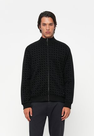 Zwarte zip-up jas met een patroontextuur. Heeft een geribbelde kraag, manchetten en zoom. Zijstrepen voegen detail toe. Gladde stofafwerking.
