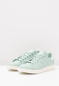 Sneaker verde menta chiaro in pelle liscia, suola in gomma bianca, chiusura con lacci, dettagli perforati sui lati e accentuazione del tallone bianco.