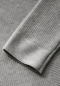 Graues Strickgewebe mit einem gerippten Bündchen und einer strukturierten Oberfläche, die weiche, gleichmäßige Maschen und eine glatte Oberfläche präsentiert.