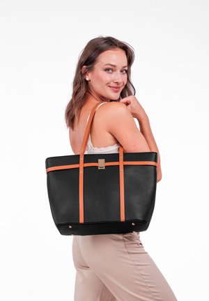 Černá taška přes rameno s oranžovými koženými popruhy a kovovým logem. Hladký povrch, obdélníkový tvar a čtyři kovové nožičky na dně.