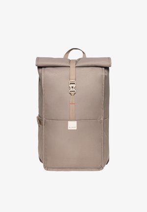 Sac à dos simple beige à rabat enroulable avec fermeture à boucle à l'avant, poignée supérieure, et patch logo VAUDE sur la poche avant.