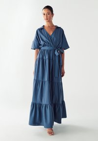 Denimové šaty ve tmavě modré barvě s krátkými rukávy, s vázacím páskem a vícestupňovými vrstvami sukně, s límečkem a volným střihem.