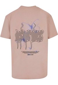 Lyserød bomulds t-shirt med et sort grafisk motiv med stiliseret tekst og blå sommerfuglemotiver på ryggen, med yderligere tekst nedenfor.