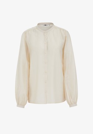 Kremasta bluza dugih rukava s okruglim izrezom, prednjim kopčanjem na gumbe, lagano napuhanih rukava i manžetnama s gumbima.