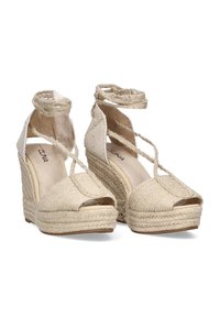 Cuñas de espadrilles beige con textura tejida, abiertas en la punta y con lazos en el tobillo. Plataforma alta y tacón texturizado para mayor soporte.