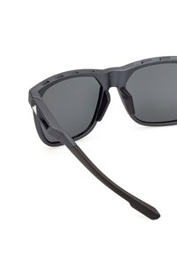 Black sports sunglasses with angular, matte frames and dark, reflective lenses. Notable texture and grip features on the arms.