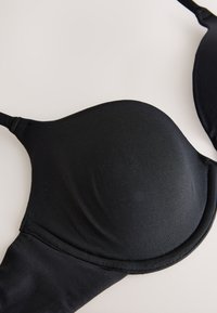 Mustast polsterdatud rinnahoidjat, millel on siledad karbid ja reguleeritavad rihmad, ühevärvilise neutraalse taustal.