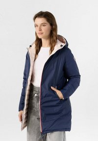 Giacca imbottita blu con fodera rosa, cappuccio e tasche con zip. Presenta una texture liscia, zip a contrasto e una forma aderente.