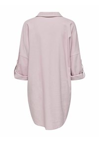 Chemise surdimensionnée rose pâle, avec un col et des manches trois-quarts, présentant un détail de revers et une coupe décontractée. Texture de tissu lisse.