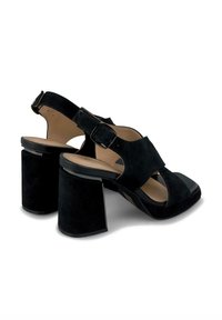 Sandales à talon bloc en daim noir avec un bout carré, un talon ouvert, une bride de cheville et une semelle lisse noire. Comprend des éléments de design découpés.