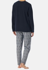 Navyblauw langemouwen shirt gecombineerd met grijs gestreepte pyjamabroek met een subtiel ontwerp. Katoenen materiaal, losse pasvorm en lichte textuur.