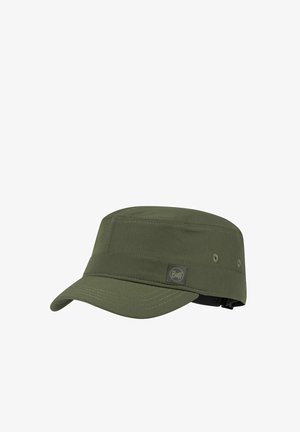Mujer con cabello largo trenzado que lleva una gorra verde oliva y una camiseta verde oliva a juego, mirando hacia su izquierda sobre un fondo blanco.