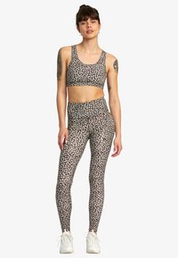 Musta aktiivivaatetus, joka sisältää istuvan cropped-topin ja korkeavyötäröiset leggingsit, joissa on valkoinen kukkakuosi ja vaaleanpunaisia yksityiskohtia.