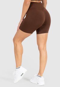 Bruine hoge taille fietsshorts gemaakt van rekbare stof, met een gladde textuur en een aansluitende pasvorm, en met een omgeslagen zoom bij de openings van de pijpen.