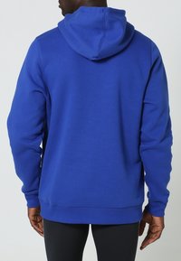 Niebieska bluza z kapturem, wykonana z bawełny, z prążkowanymi mankietami i dołem. Gładka tekstura, kangurza kieszeń i widoczne detale szwów.