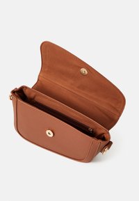 Sac bandoulière en cuir marron avec une finition texturée, doté d'une fermeture à pression, d'une poche intérieure zippée et d'une doublure intérieure lisse.