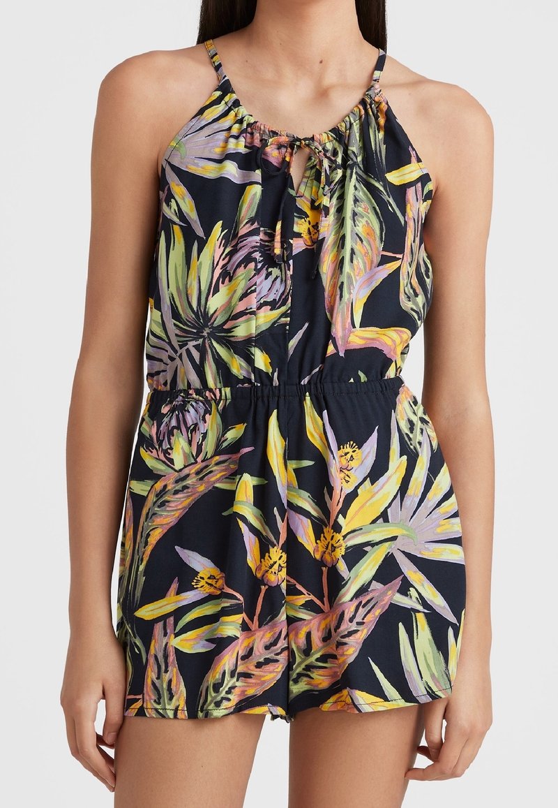 Combinaison imprimée tropicale sans manches avec un décolleté en trou de serrure et un lien, taille élastique, présentant des feuilles vertes, jaunes et violettes sur un fond sombre.