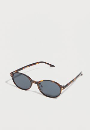 Okrugle sunčane naočale s tamnim lećama i tankim plastičnim okvirom u uzorku kornjačevine na bijeloj pozadini.