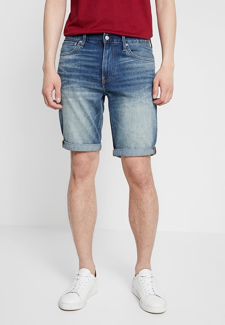 Denimshorts i en ljus till mörkblå gradient, uppvikt fåll, framfickor, knapstängning, kompletterat med vita sneakers.
