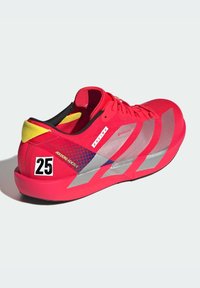 Rode sportschoenen met een slank design, voorzien van zilverkleurige accenten, een gele hiel en een gecheckerd paneel. Toont het nummer "25" aan de zijkant.